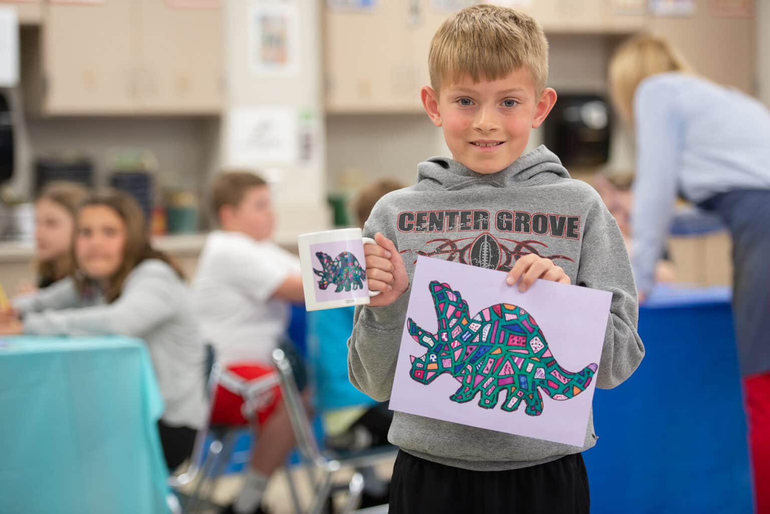 Work with Art to Remember to set up an Art Fundraiser for Schools image shows child holding up dinosaur drawing
