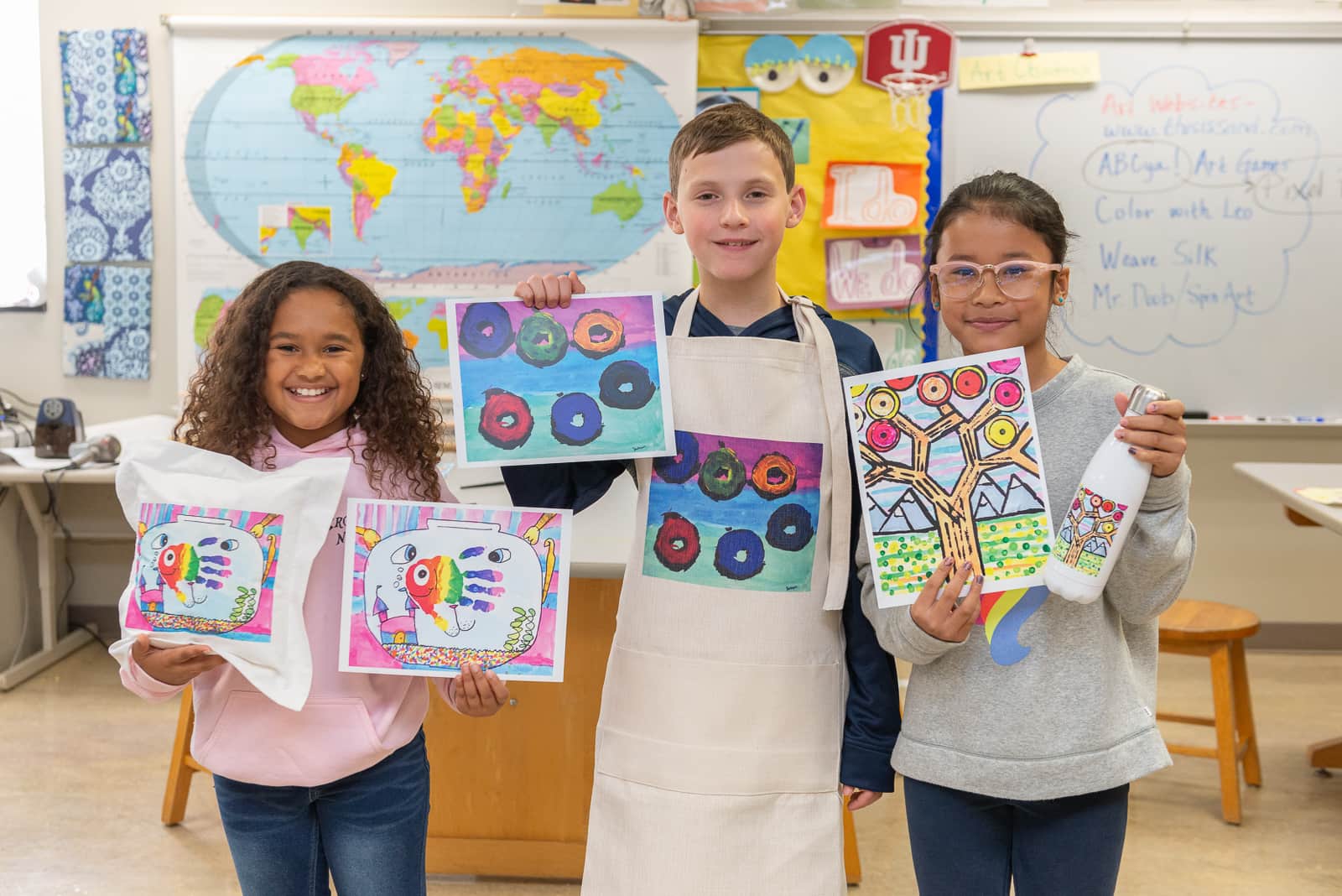 Host an Art Fundraiser for Schools with Art to Remember image shows kids holding up pieces of artwork