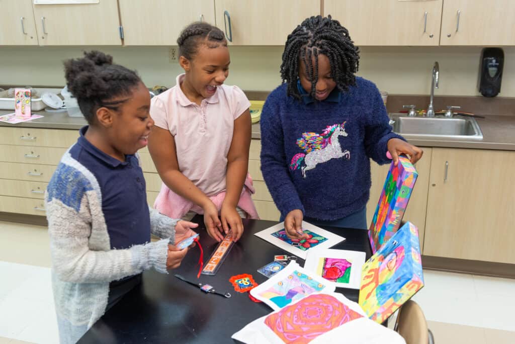Work with the Art to Remember team to host an Art Fundraiser for Schools image shows three kids looking at art